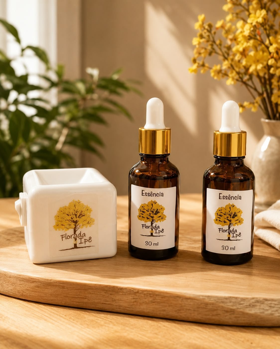 Dois frascos de essência de 30 ml com conta-gotas dourado e um aromatizador de cerâmica branca com o logo da marca